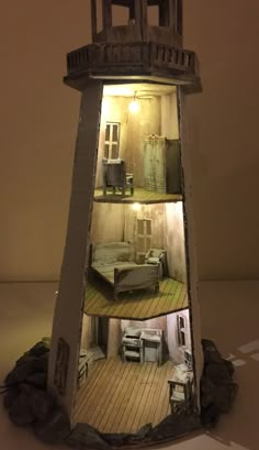 a miniature lighthouse made out of cardboard with pictures on the top and bottom part showing furniture inside