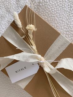 a package wrapped in brown and white paper with a tag on it that says nicole