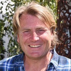 a close up of a person wearing a blue and white checkered shirt smiling at the camera