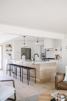 an open concept kitchen and living room with white walls, wood flooring and modern furnishings