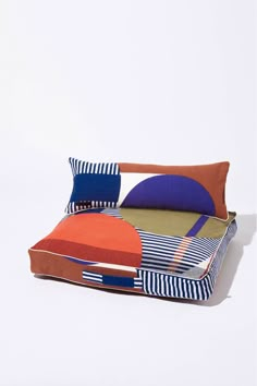 a bed with colorful pillows on top of it and a white wall in the background