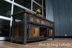 an old wooden cabinet with glass doors and flowers in the window sill next to it