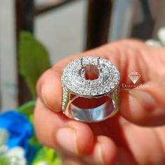 a person holding a diamond ring in their hand with the center surrounded by smaller diamonds