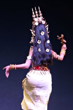 a woman with long blue hair and gold jewelry on her head is standing in front of a black background