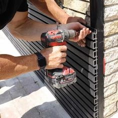 a man is using a drill to fix a brick wall with two power tools on it