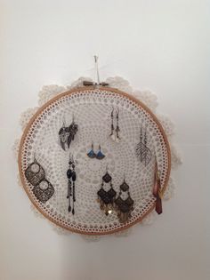 a white doily with earrings hanging from it's sides and on the wall