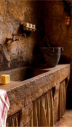 a stone bathroom with a sink and soap dispenser