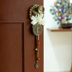 Glass beads in sublime hues form Mony Lemus's classic door knob hanger, infused with the region's traditional glamour. The piece has polyester braids in matching hues, from which charms dangle serenely. A zamac metal Saint Benedict's medal rests at the front, decorated by an ivory ribbon. Beaded Door, Door Knob Hanger, Doorknob Hangers, Classic Doors, Spiritual Decor, Saint Benedict, Mens Jewelry Necklace, Premium Gift, Door Knob