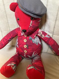 a red teddy bear with a hat on it's head sitting on a couch