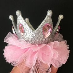 a hand holding a pink and silver princess crown