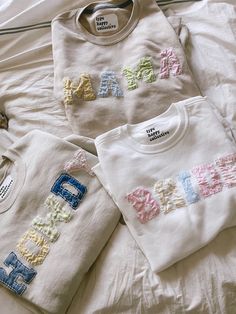 three personalized t - shirts are laid out on a white bed with the word dad spelled in multicolored letters