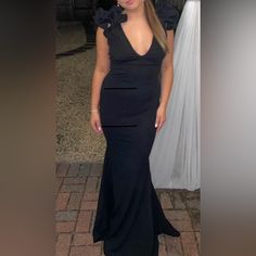 a woman in a long black dress posing for a photo with her hair pulled back