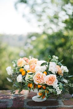 a bouquet of flowers sitting on top of a wooden table in front of some trees