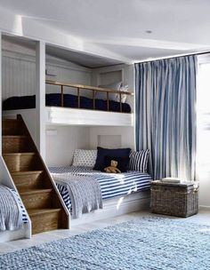 a bedroom with bunk beds and blue striped curtains on the windowsill, along with a rug