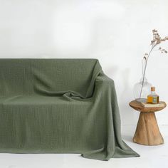 a green blanket sitting on top of a wooden table next to a vase with flowers