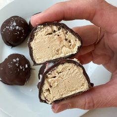 someone is holding three chocolate covered desserts on a plate