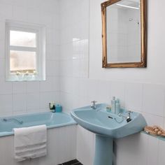 a bathroom with a blue sink, mirror and bathtub in the middle of it