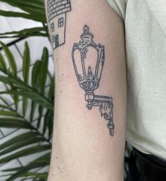 a man with a tattoo on his arm that has a house and lamp in it