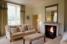 a living room filled with furniture and a fire place in front of a mirror on the wall