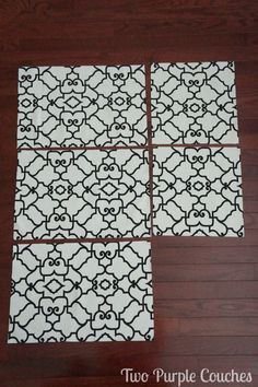 four black and white tiles sitting on top of a wooden floor