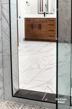 a bathroom with marble flooring and wooden cabinetry in the shower area, along with a large mirror