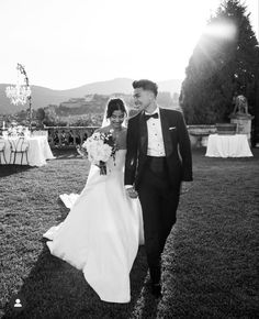 a bride and groom walking through the grass at their wedding reception in front of an outdoor venue