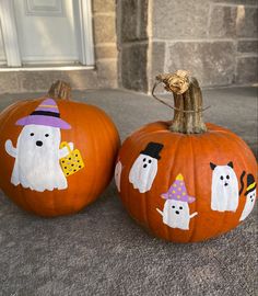 two painted pumpkins sitting on the ground next to each other with ghost and dog faces