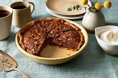 a pie sitting on top of a table next to cups and saucers