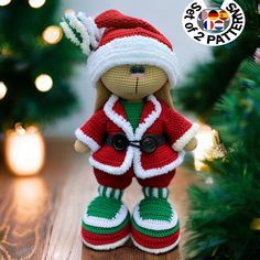 a crocheted teddy bear wearing a red and white christmas outfit next to a christmas tree