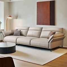 a living room filled with furniture next to a large painting on the wall above a window