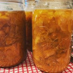 two jars filled with food sitting on top of a red and white checkered table cloth