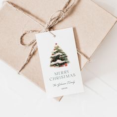 a gift wrapped in brown paper with a merry christmas tree tag on the front and bottom