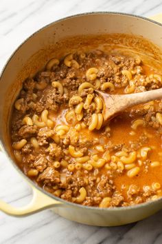 a large pot filled with pasta and meat in sauce on top of a marble counter