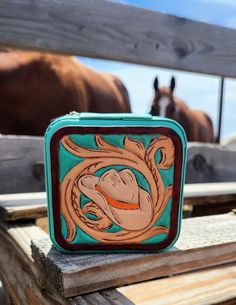 a small square box with an image of a horse in the center on top of a wooden fence