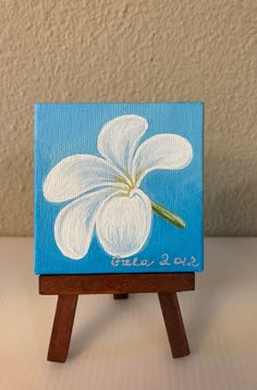 a small easel with a white flower painted on it