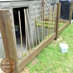 a wooden fence that has been built into the side of a house with grass growing in it