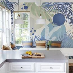 a white kitchen with blue and green wallpaper on the walls, along with a breakfast nook