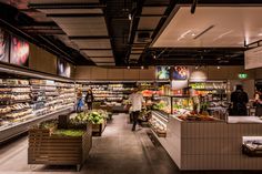 people are shopping in the produce section of a grocery store with shelves full of food