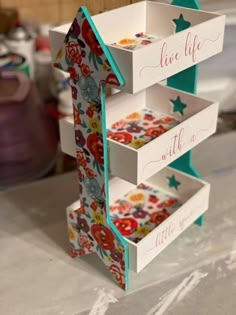 three tiered card box with flowers and stars painted on it, sitting on top of a table