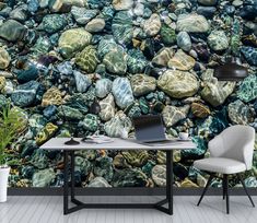 a desk with a laptop on it in front of a wall that has rocks all over it