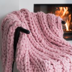 a pink blanket sitting next to a fire place