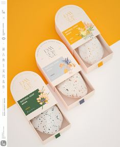 three boxes with different types of soaps in them on a yellow and white background