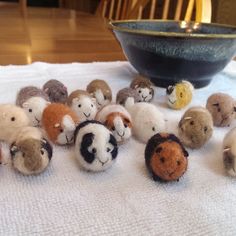 small stuffed animals sitting on top of a white table cloth next to a black bowl