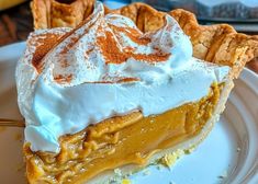 a slice of pumpkin pie with whipped cream on top is sitting on a white plate