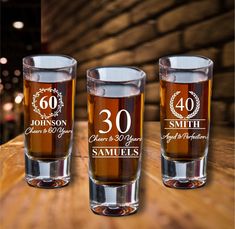 three shot glasses sitting on top of a wooden table with the number 30 printed on them