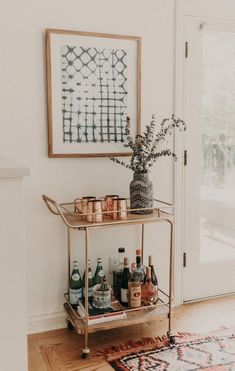 a bar cart with liquor bottles on it in front of a door and a rug