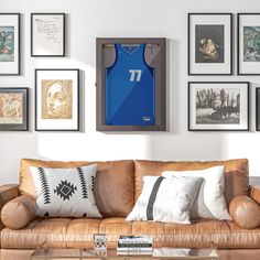 a living room filled with furniture and framed pictures on the wall above him is a basketball jersey