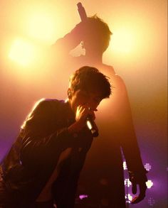 a man holding a microphone up to his face while standing in front of a crowd