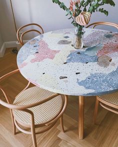 a round table with four chairs and a vase filled with flowers on top of it