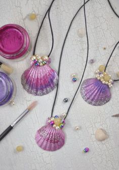 three seashells are sitting on a table next to some beads and other items